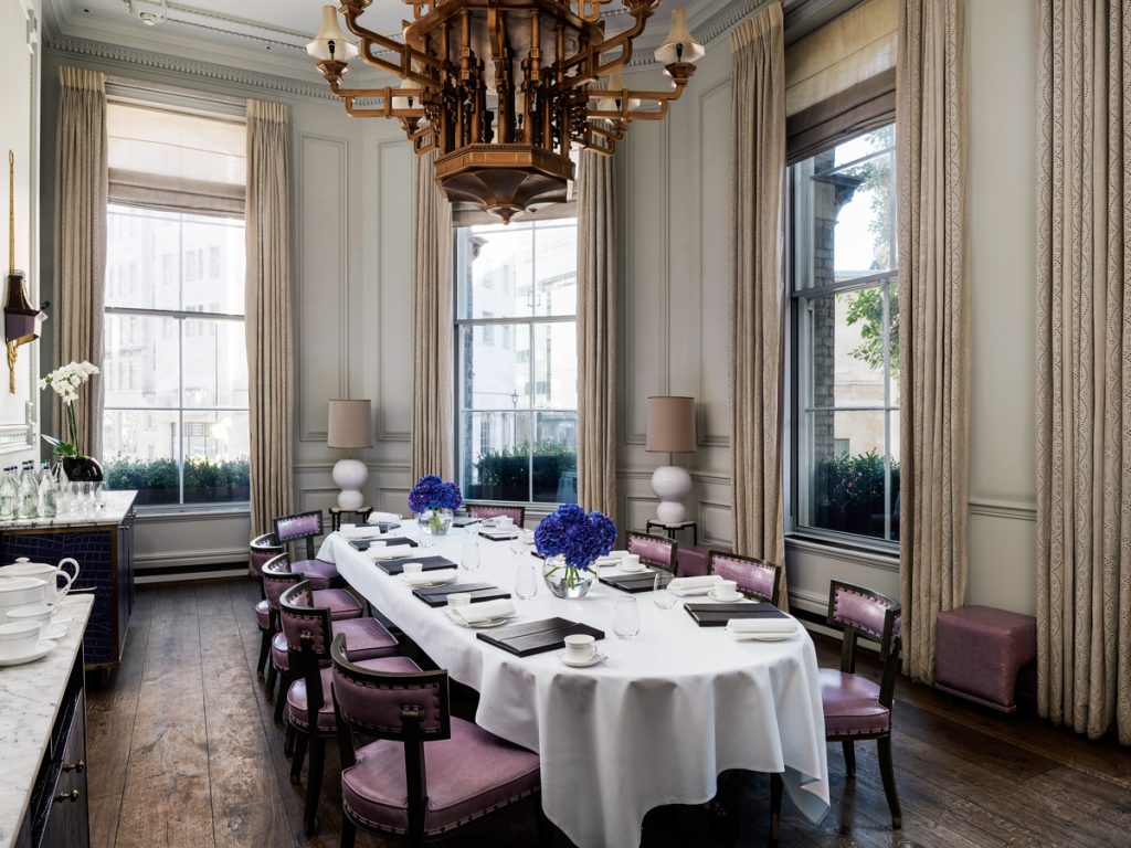 Daytime view of Postillion room with table laid in boardroom style with notepads, coffee cups, water glasses, and small vases of bright blue flowers.
