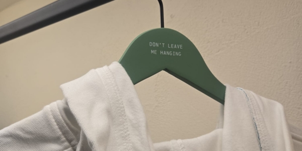 a robe hanging on a green hanger with a green sign on the hanger that reads 'Don't leave me hanging'